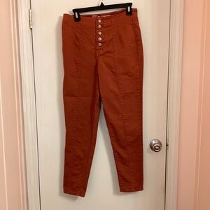 Terracotta colored jeans with buttons up the front